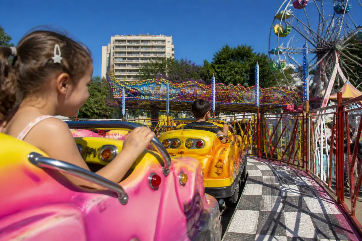 Enfants sur autos tamponneuses à la fête foraine de Marseille sous un ciel bleu