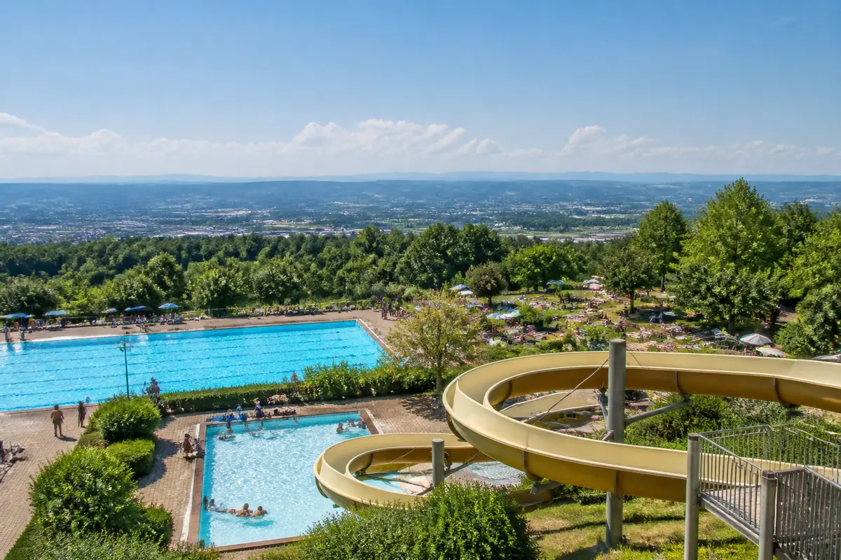 Piscines et toboggan dans un terrassenbad avec vue panoramique sur la vallée verdoyante